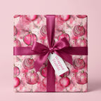 Wrapped Studios pink Christmas wrapping paper with ornament design and dark pink ribbon.