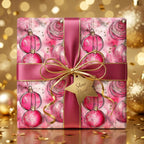 Christmas gift wrapped in pink ornament pattern paper with satin ribbon and gold bow.