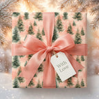 Elegant pine tree pink Christmas wrapping paper with a peach satin bow and gift tag by Wrapped Studios.