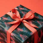 Forest Christmas wrapping paper with pink pine trees and a coral ribbon bow by Wrapped Studios.