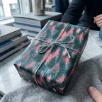 Teal and pink forest wrapping paper by Wrapped Studios on a gift box tied with a silver twine bow.