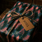 Pine tree Christmas wrapping paper with a twine bow and NOEL gift tag by Wrapped Studios.