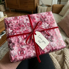 Floral Christmas wrapping paper with red velvet ribbon and "Love you sis" tag.