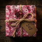 Elegant floral Christmas gift wrap in pink with twine bow and "Joy" tag.