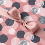Blush pink gift wrapping paper with polka dot pattern and satin ribbon bow.