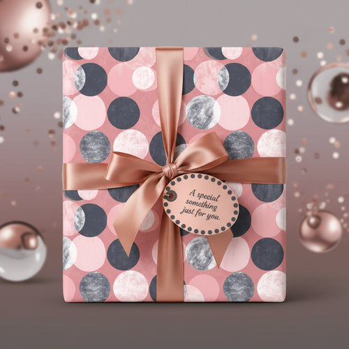 Blush pink gift wrapped in modern circle patterned wrapping paper with satin ribbon bow.