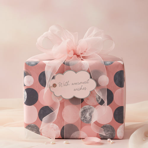 Elegant gift wrapped in pink polka dot wrapping paper with a sheer ribbon and "With warmest wishes" tag.