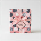 Blush pink gift wrapped with modern dot patterned wrapping paper and a delicate pink ribbon.