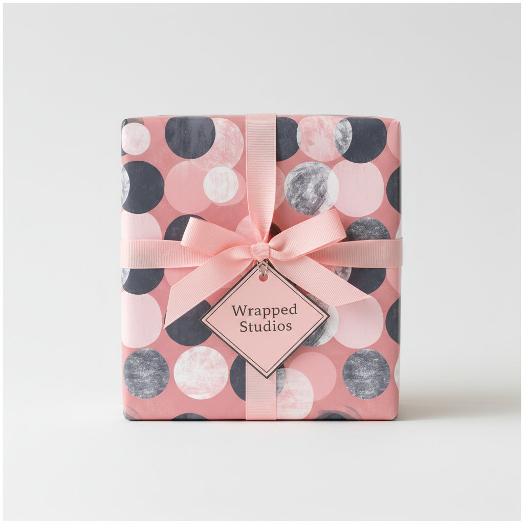 Blush pink gift wrapped with modern dot patterned wrapping paper and a delicate pink ribbon.