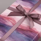 Elegant gift wrapped in pink and purple watercolor wrapping paper with a mauve satin ribbon and bow.