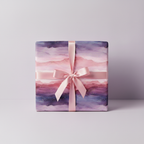 Elegant gift with pink ribbon, wrapped in watercolor abstract wrapping paper with purple, pink, and gold accents.