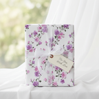 Elegant floral wrapping paper with purple and pink blossoms, tied with a white ribbon and "For You, With Love" tag, perfect for luxury gift wrapping.