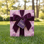 Elegant gift wrapped in pink floral wrapping paper with a velvet purple ribbon and "For You" tag.