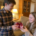 Boy giving girl a gift in pink floral wrapping paper with burgundy ribbon. Rose gift wrap by Wrapped Studios.