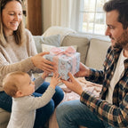 Parents giving baby a gift wrapped in teddy bear wrapping paper with a pink bow by Wrapped Studios.