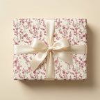Elegant pink floral wrapping paper with a cream satin bow on a gift box by Wrapped Studios.