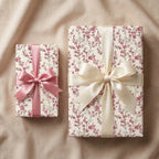 Elegant floral wrapping paper with pink and cream satin bows on gift boxes by Wrapped Studios.