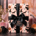 Pink Halloween wrapping paper with cute ghosts and pumpkins, tied with a black satin bow by Wrapped Studios.