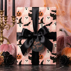 Pink Halloween wrapping paper with cute ghosts and pumpkins, tied with a black satin bow by Wrapped Studios.