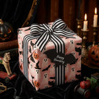 Pink Halloween wrapping paper with ghosts and bats on a gift box by Wrapped Studios.