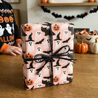 Cute pink Halloween wrapping paper with ghosts and bats on a gift tied with black ribbon by Wrapped Studios.