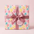 Watercolor balloon birthday wrapping paper with a pink satin bow by Wrapped Studios.