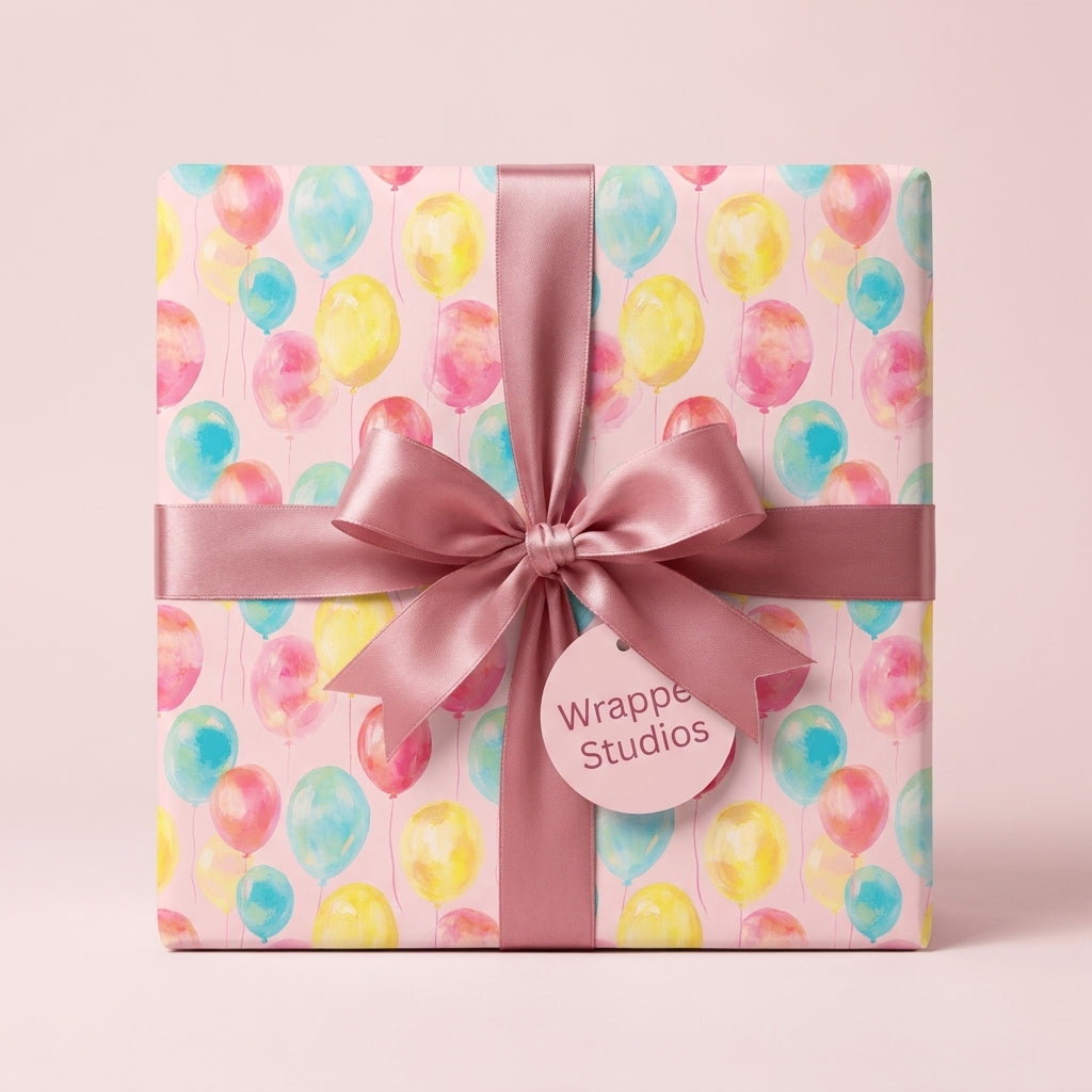 Watercolor balloon birthday wrapping paper with a pink satin bow by Wrapped Studios.