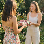 Friends exchanging a birthday gift in luxury floral wrapping paper with a pink ribbon. Wrapped Studios.