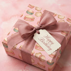 Pink watercolor drum birthday wrapping paper with a mauve ribbon and Happy Birthday tag by Wrapped Studios.
