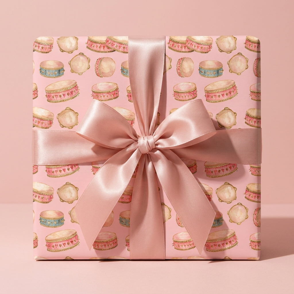 Pink baby shower wrapping paper with watercolor drums and a satin bow, by Wrapped Studios.