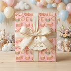 Pink baby shower wrapping paper with watercolor drums and a cream bow by Wrapped Studios.