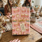 Boho pink wrapping paper with a whimsical tambourine print by Wrapped Studios, tied with rustic twine.