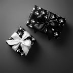 Playful black and white monkey wrapping paper on gift boxes with satin bows by Wrapped Studios.
