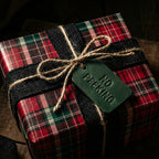 Rustic Christmas gift wrap with a red and green plaid pattern, tied with a twine bow and burlap ribbon.