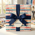 Striped watercolor gift wrap from Wrapped Studios, tied with a navy ribbon and "Celebrate!" tag.