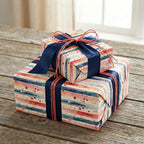 Two stacked gifts wrapped in watercolor stripe wrapping paper with blue ribbon, on wooden table.