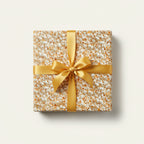 Square gift box wrapped in popcorn patterned wrapping paper with a gold satin ribbon and bow.