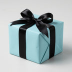 Light blue gift box wrapped with black satin ribbon and bow.
