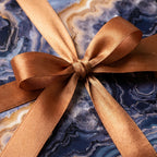 Blue agate luxury gift wrap with a copper satin ribbon bow, geode wrapping paper by Wrapped Studios.