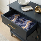 Luxury navy blue and gold agate wrapping paper by Wrapped Studios lining a dark dresser drawer.
