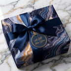 Luxury navy and gold marble wrapping paper with satin ribbon bow on a gift box by Wrapped Studios.