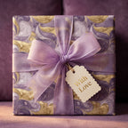 Luxury purple and gold marble wrapping paper with a lavender ribbon and gift tag by Wrapped Studios.