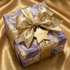 Purple marbled luxury gift wrap with a metallic gold bow and Celebrate tag by Wrapped Studios.