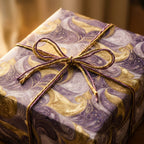 Luxury purple and gold marbled wrapping paper with a twine bow on a gift box by Wrapped Studios.