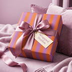 Luxury purple and orange striped wrapping paper with a pink satin ribbon bow by Wrapped Studios.