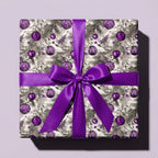 Elegant purple Christmas wrapping paper with ornament design and satin bow by Wrapped Studios.