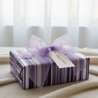 Purple striped gift wrap with a sheer lavender ribbon and a decorative tag, perfect for a birthday or special occasion.