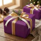 Elegant purple wrapping paper on gifts with gold ribbon and evergreen sprigs; luxury holiday present.