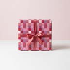 Red patchwork print wrapping paper with a matching satin ribbon, ideal for birthday or holiday gifts.