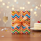 Celebratory gift wrapped in colorful chevron wrapping paper with an orange bow, cake, and champagne.